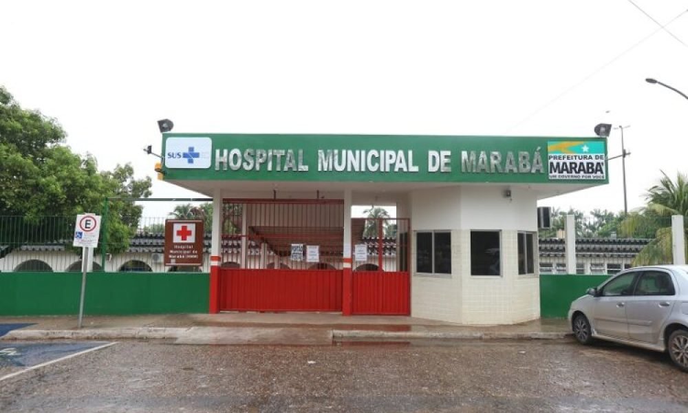 Entrada do Hospital Municipal de Marabá com letreiro verde e portão vermelho, sinalização SUS e Prefeitura
