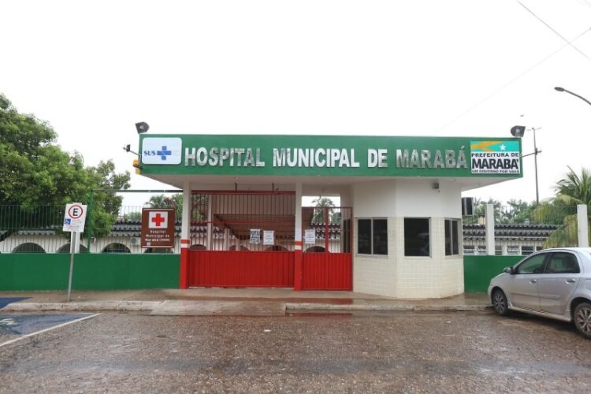 Entrada do Hospital Municipal de Marabá com letreiro verde e portão vermelho, sinalização SUS e Prefeitura