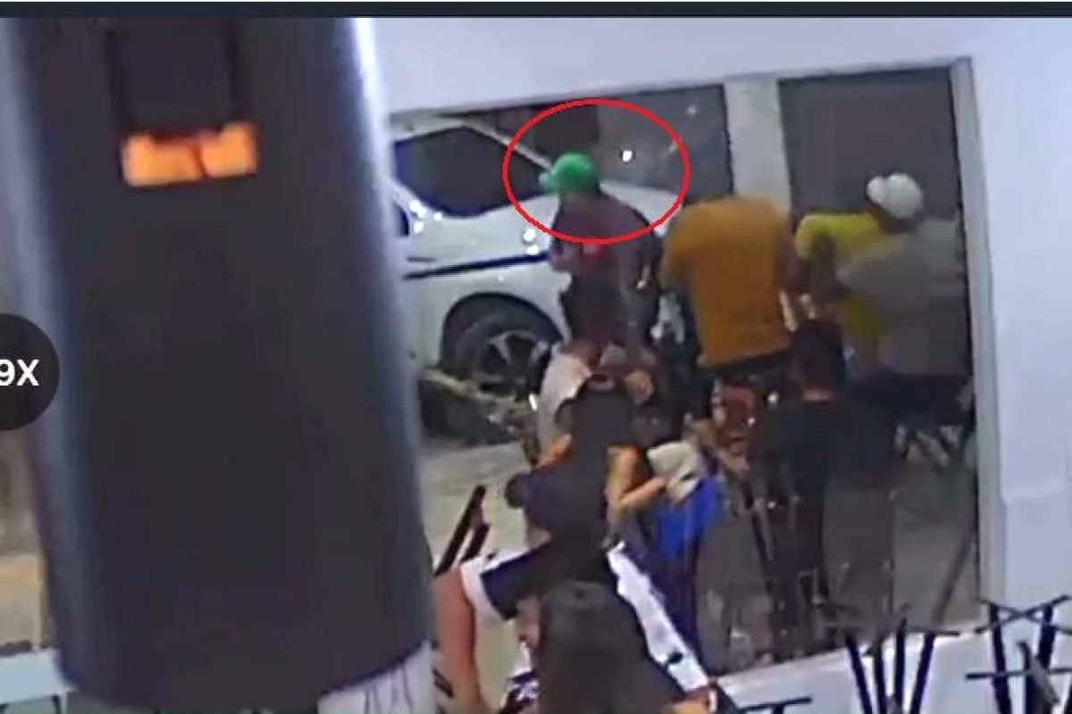 Grupo de pessoas em ambiente interno com carro branco ao fundo.