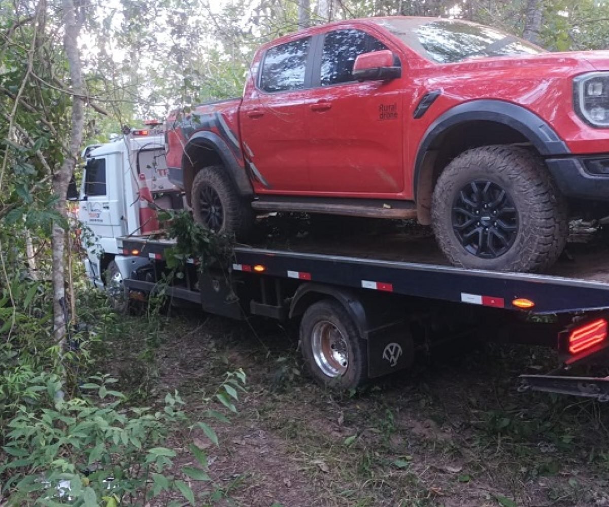 Camionete Ford Ranger Raptor vermelha sendo transportada por um guincho em área de mata.