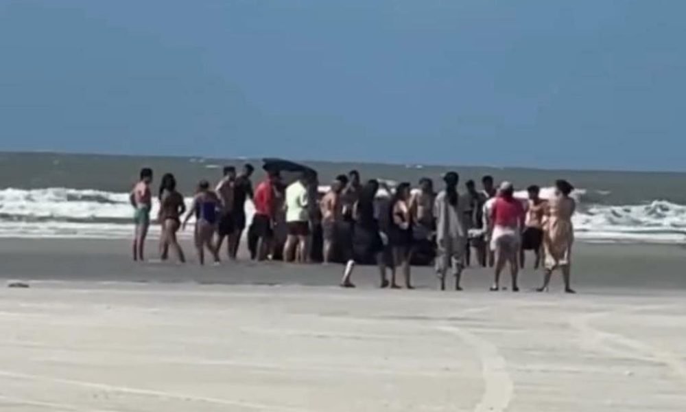 banhistas e mostrou várias pessoas em volta tentando desatolar o veículo. A prai