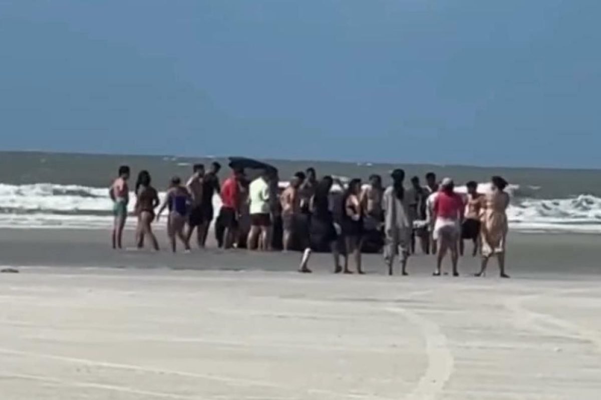 banhistas e mostrou várias pessoas em volta tentando desatolar o veículo. A prai