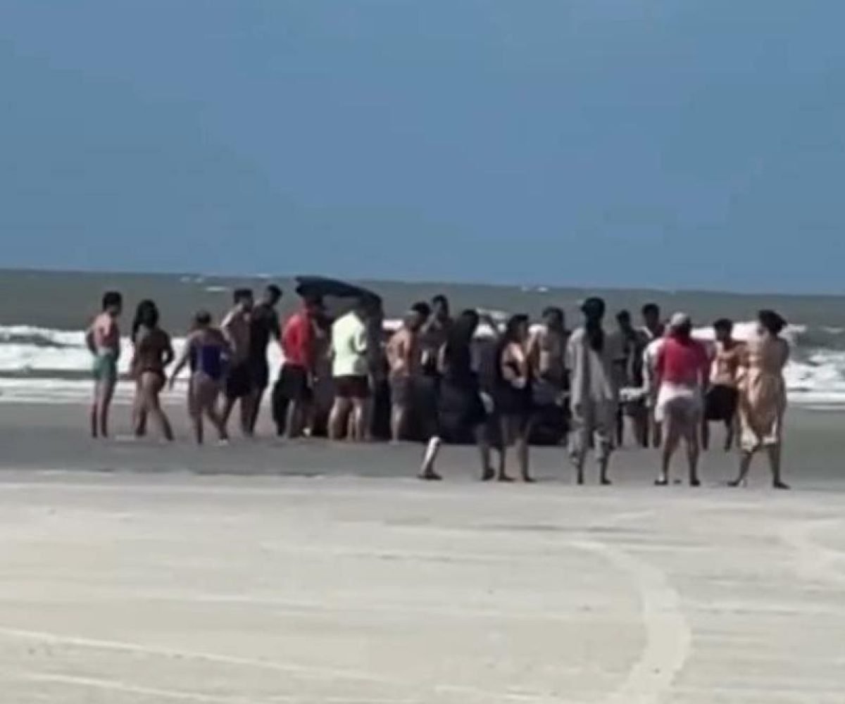 banhistas e mostrou várias pessoas em volta tentando desatolar o veículo. A prai